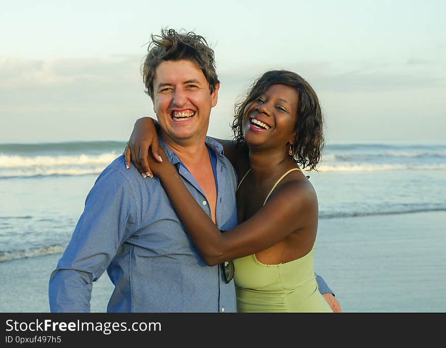 Happy and beautiful mixed ethnicity couple with beautiful afro American women and cheerful Caucasian men enjoying holidays honeymoon trip on beach cuddling sweet in multiracial love. Happy and beautiful mixed ethnicity couple with beautiful afro American women and cheerful Caucasian men enjoying holidays honeymoon trip on beach cuddling sweet in multiracial love