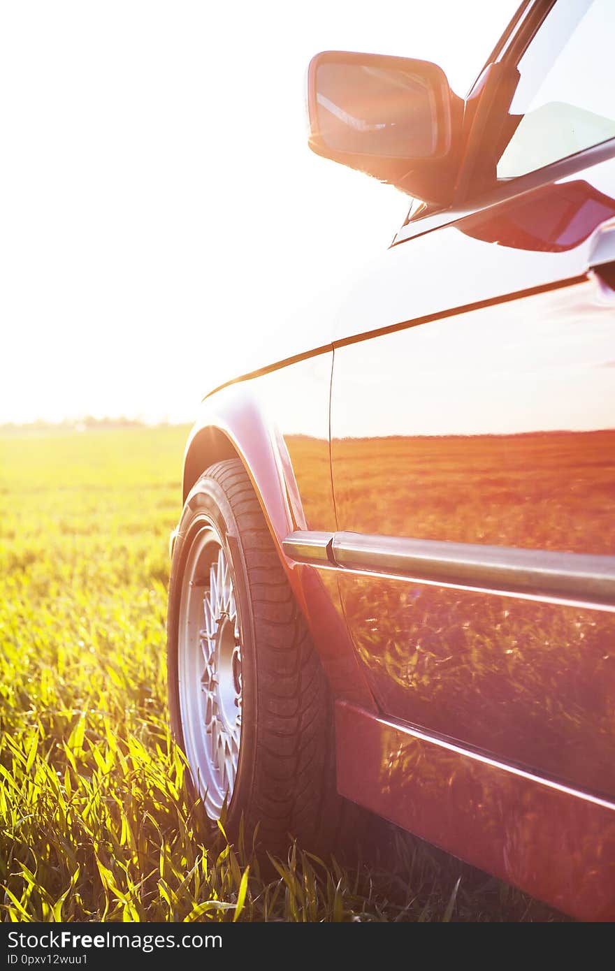 Front left side of an old German car that stands on green grass at sunset