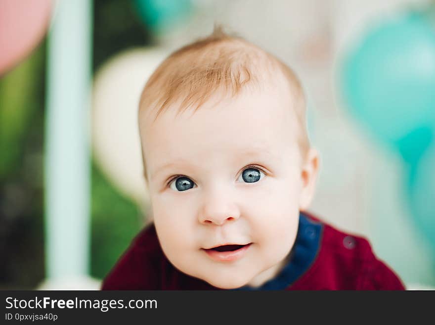 Sweet baby boy with big blue eyes lying on belly and smiling.