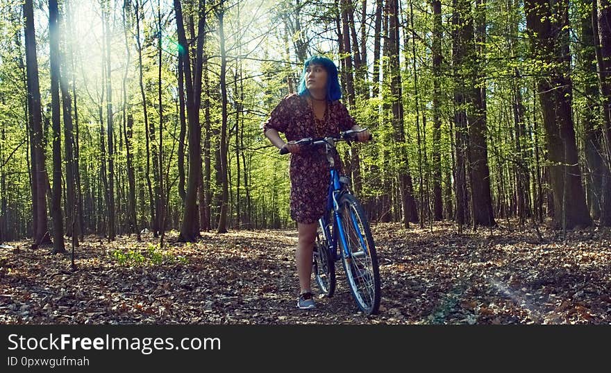 The girl in the dress rides a bicycle through the forest.