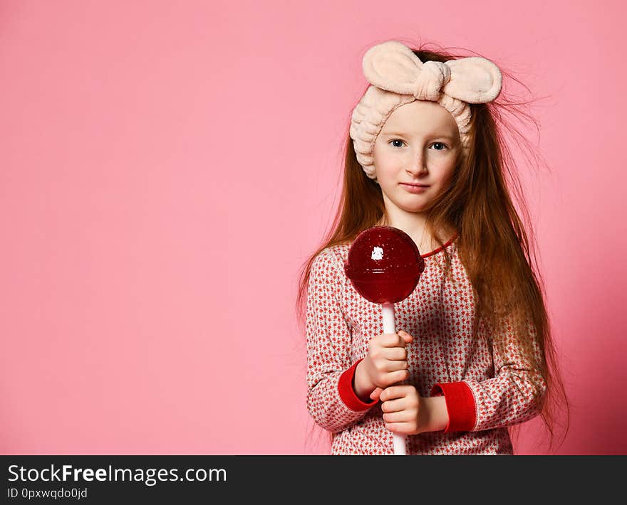 Funny child with candy lollipop, happy little girl eating big sugar lollipop