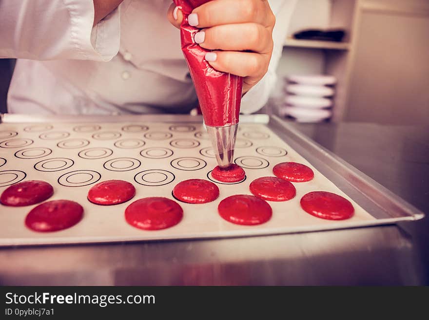 Conscious work. Professional confectioner using piping bag while putting dough on baking tray. Conscious work. Professional confectioner using piping bag while putting dough on baking tray