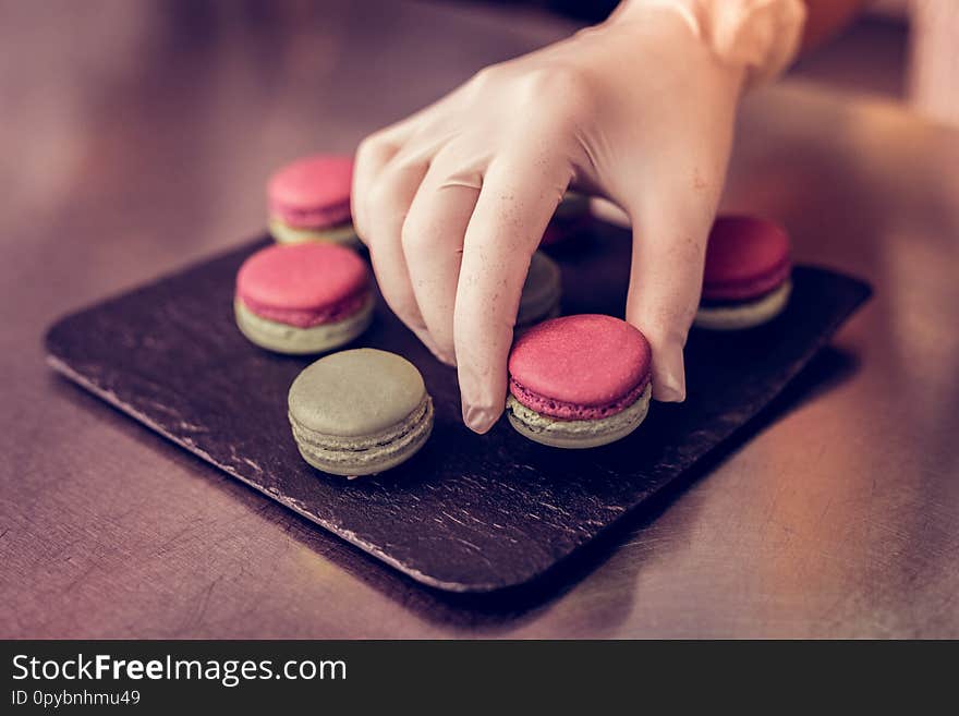 Lets try. Close up of female hand that taking macaron from plate, going to sell it. Lets try. Close up of female hand that taking macaron from plate, going to sell it