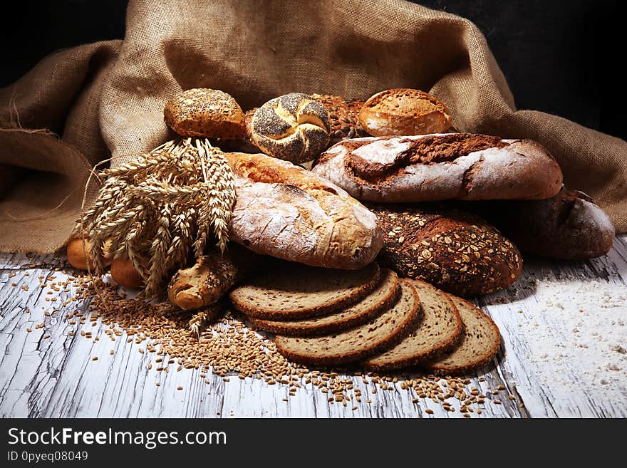 Assortment of baked bread and bread rolls on rustic table background. Assortment of baked bread and bread rolls on rustic table background