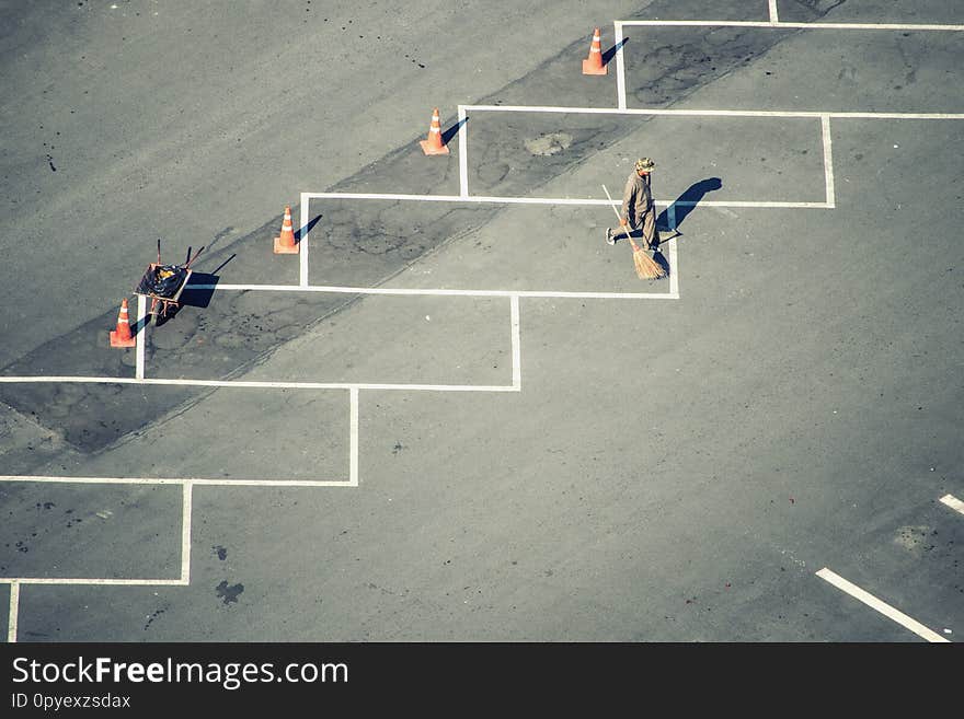 Men Are Cleaning The Paved Road Of The Parking Lot.