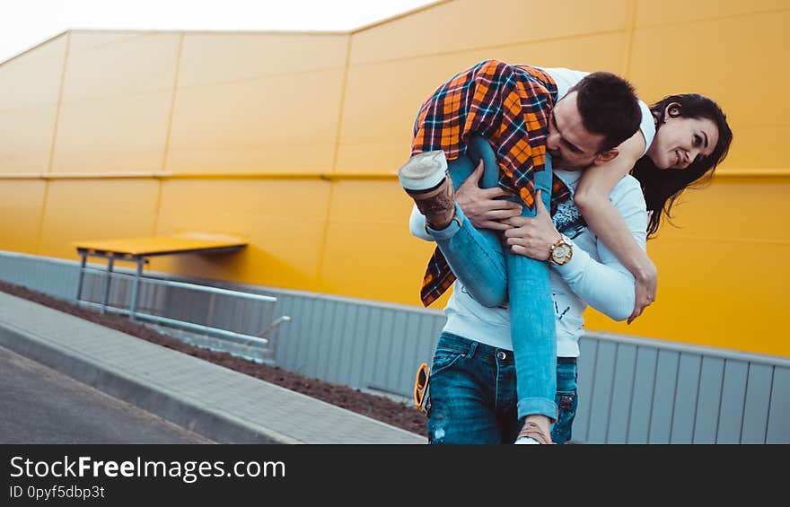 Happy men carrying his girlfriend on yellow background - couple in love. Happy men carrying his girlfriend on yellow background - couple in love