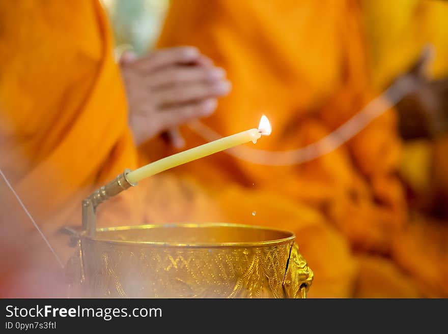 Buddha monk hold candlestick above holy water bowl. religion ceremony.