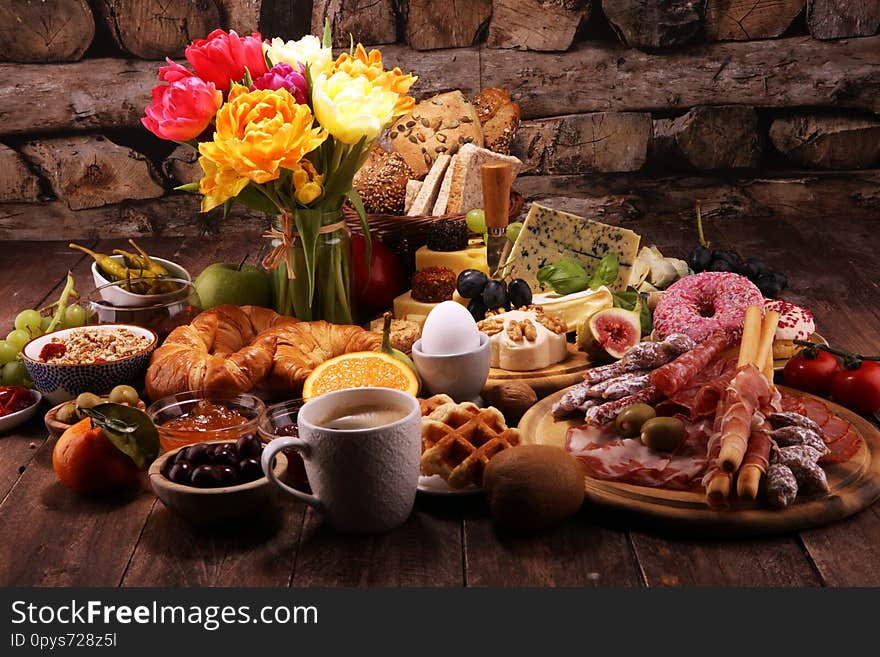 Breakfast on table with bread buns, croissants, coffe and eggs