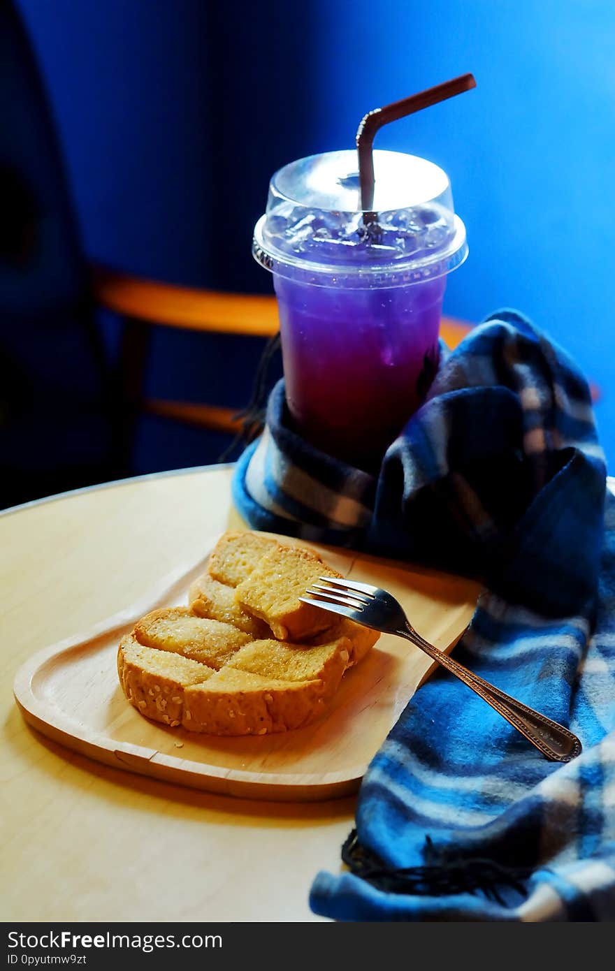 Butter toasted bread on wood trey and ice sour purple butterfly pea juice blue table wood table set with blue tone background