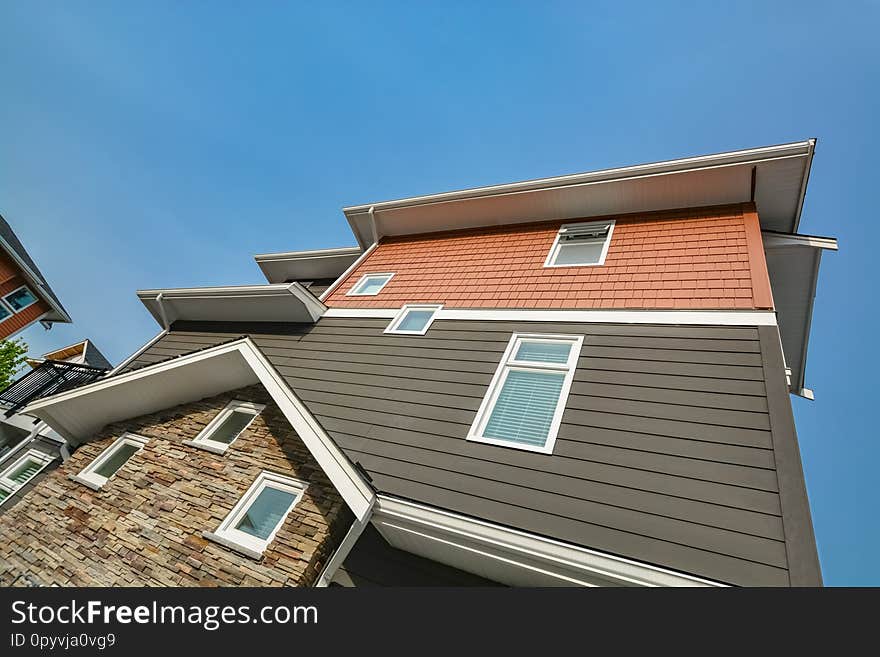 Side wall of brand new residential triplex townhouse on blue sky background. Family house for sale