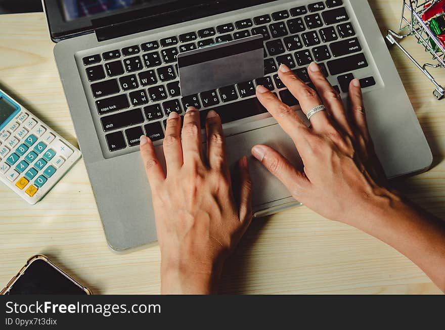Hands holding a credit card and using a laptop computer on the table. Hands holding a credit card and using a laptop computer on the table