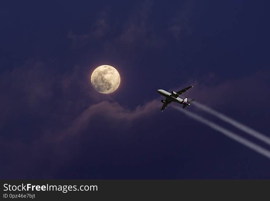 A plane flying towards a beautiful moonlight