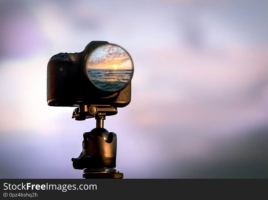 A sunset is reflected in the lens of a professional slr camera. A sunset is reflected in the lens of a professional slr camera