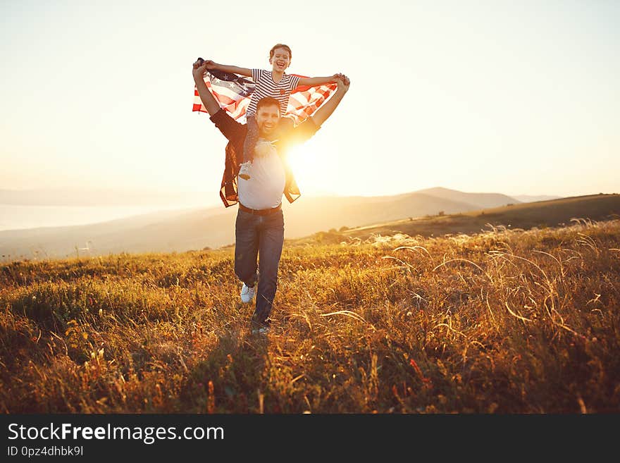 Happy family father and child  with flag of united states enjoying  sunset on nature