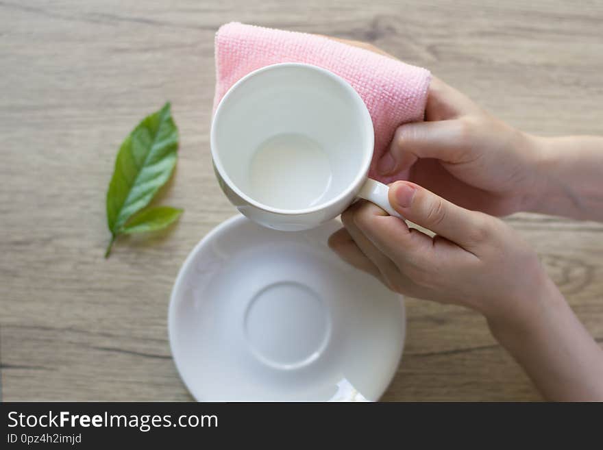 Close up woman hand cleaning coffee cup on the morning with microfiber cloth,Close up woman hand cleaning coffee cup on the rustic wood table.