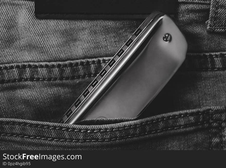 Close up of shiny blues harmonica in the blue jean pocket ,musical concept and white and black photos. Close up of shiny blues harmonica in the blue jean pocket ,musical concept and white and black photos