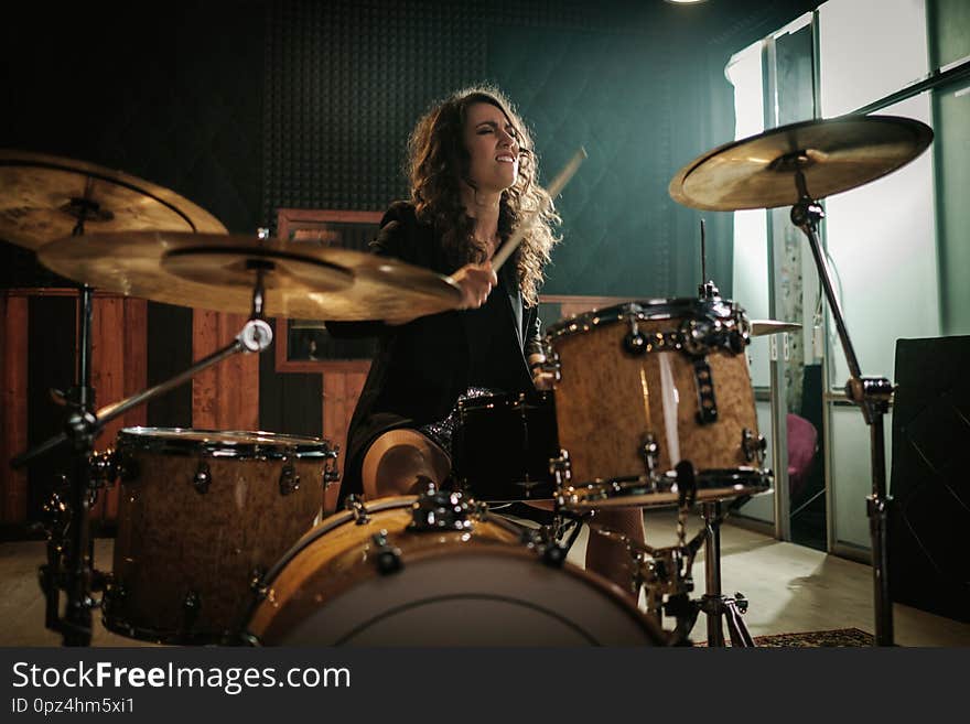 Woman playing drums during music band rehearsal.