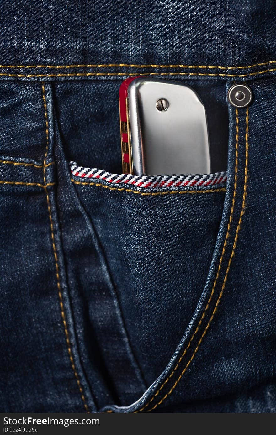 Close up of shiny blues harmonica in the blue jean pocket,musical concept and beautiful objects. Close up of shiny blues harmonica in the blue jean pocket,musical concept and beautiful objects