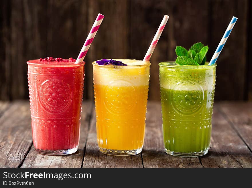 Three smoothies with fine detail decoration on top of them, various fruit smoothies