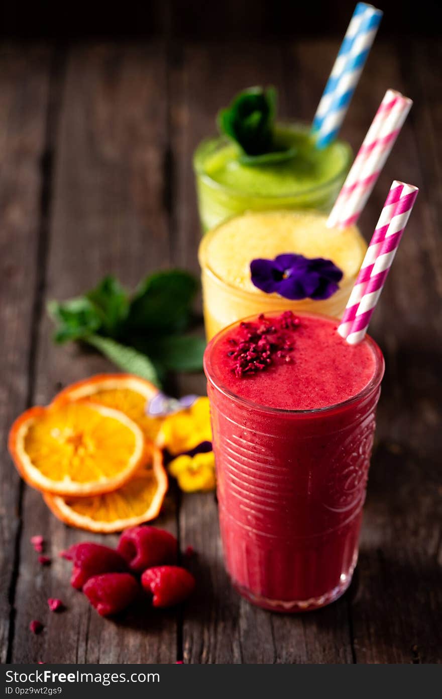 Smoothies of delicious taste decorated with green leaves, fruit slices and fruits served on the wooden table