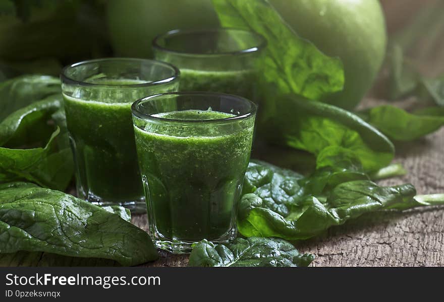 Green spinach detox smoothies with apples and lemon in glasses, selective focus