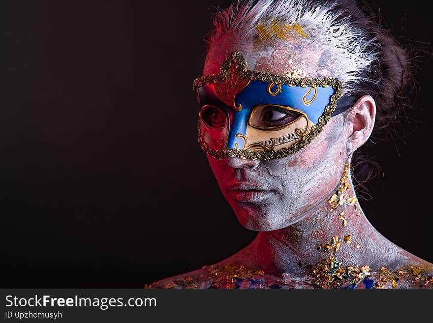 Portrait of a young masked woman with creative makeup on the theme of Venice Carnival. Portrait of a young masked woman with creative makeup on the theme of Venice Carnival