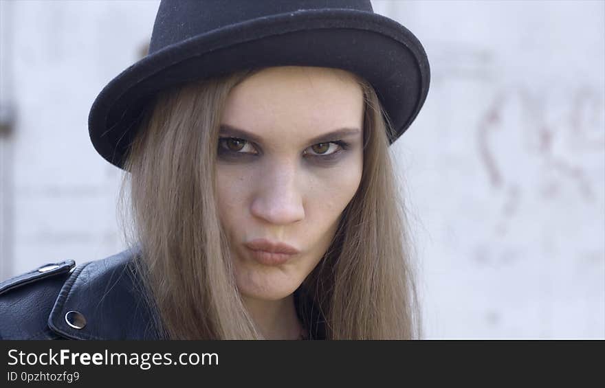 Outdoor fashion portrait of stylish young woman having fun, emotional face, laughing, looking at camera. Action. Black hat. Spring or fall outfit.