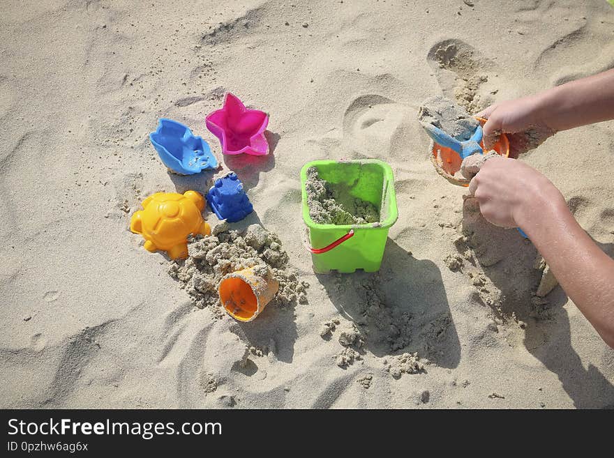 Colored children`s toys on the sandy beach on sunny days