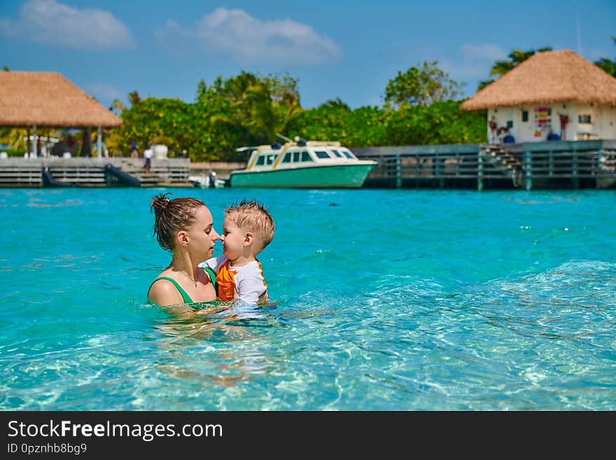 Three year old toddler boy on beach eskimo kissing his mother. Summer family vacation at Maldives. Three year old toddler boy on beach eskimo kissing his mother. Summer family vacation at Maldives