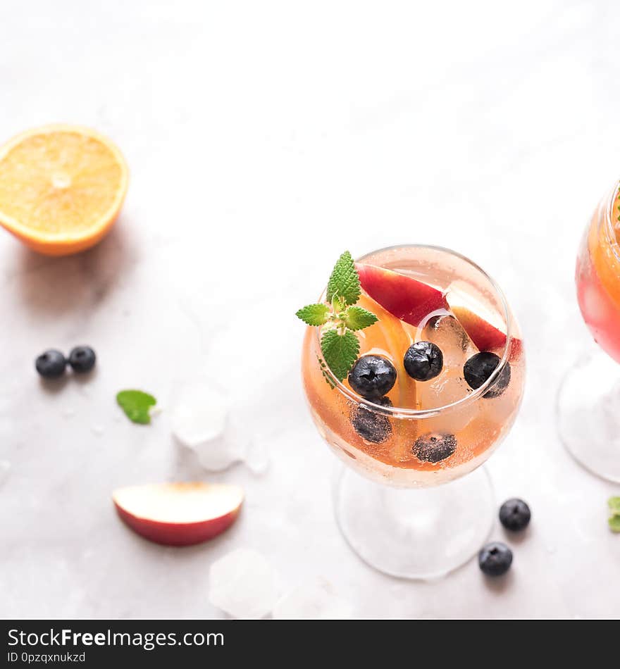 White Wine Sangria drink with Fruits and Blueberries on white marble, copy space. Glass of cold summer iced white sangria cocktail. White Wine Sangria drink with Fruits and Blueberries on white marble, copy space. Glass of cold summer iced white sangria cocktail