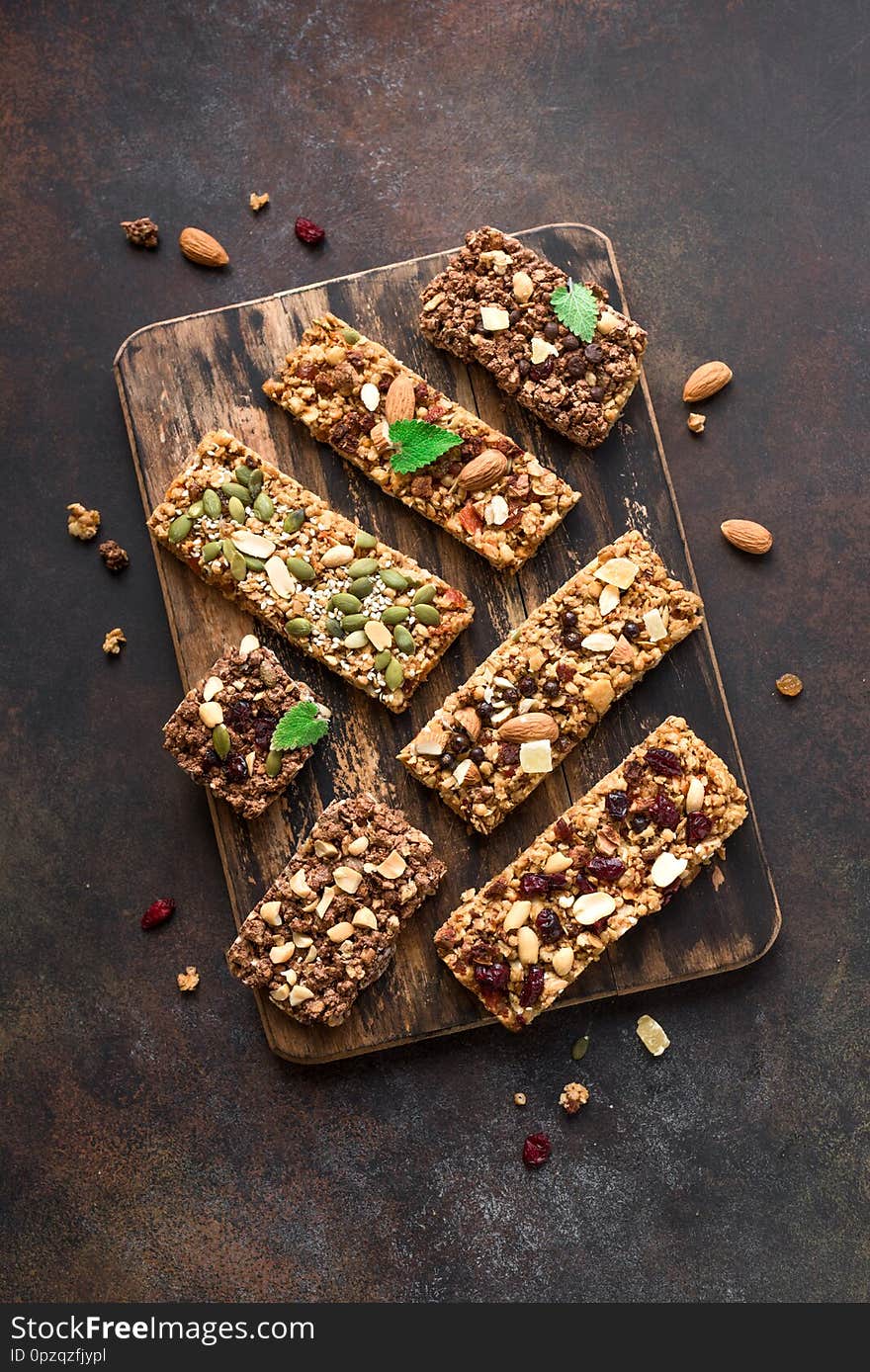 Various granola bars on dark rustic background, top view. Homemade healthy snack - granola superfood bars