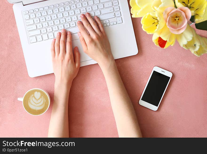 Top view shot of woman typing on white laptop computer, concrete textured table background. Feminine workspace with flowers bouquet. Close up, copy space. Top view shot of woman typing on white laptop computer, concrete textured table background. Feminine workspace with flowers bouquet. Close up, copy space