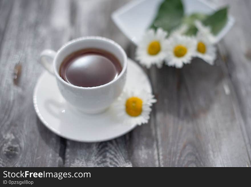 Tea In A White Cup On A Wooden Table. Daisies On The Table