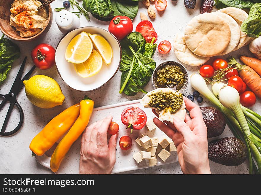 Cooking healthy vegetarian food background. Vegetables, hummus, pesto and fruits, top view. Cooking healthy vegetarian food background. Vegetables, hummus, pesto and fruits, top view