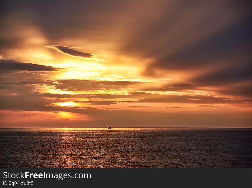 Scene of sunrise and beautiful sky background. Silhouette of a fisherman on longtail boat in the sea