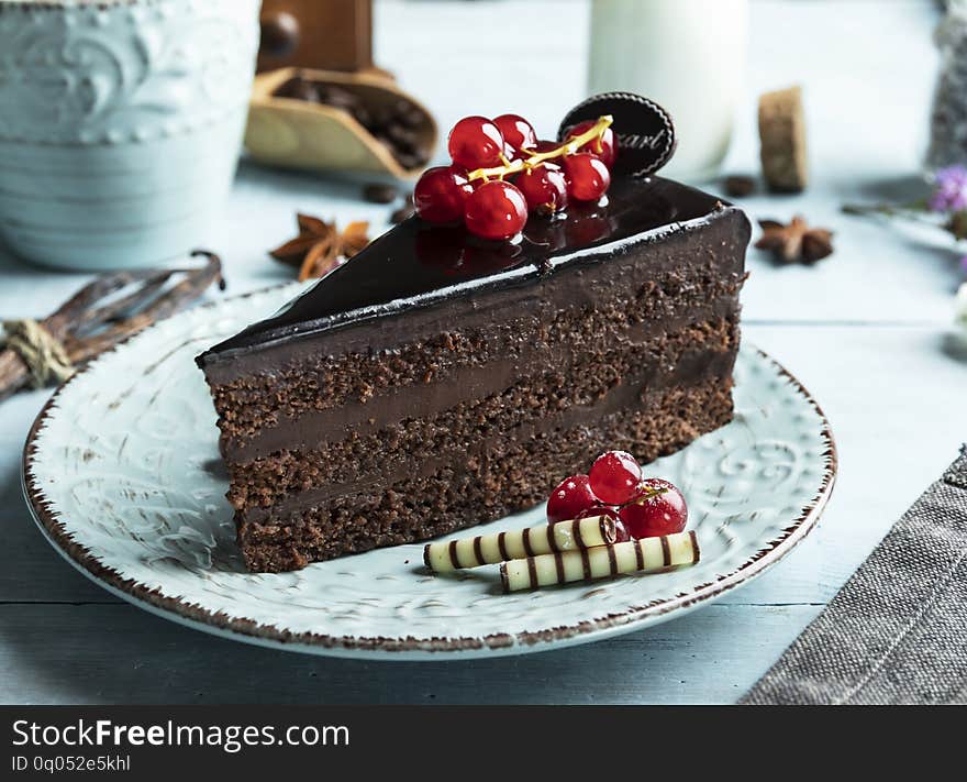 Dark chocolate cake mozart , red currant on the table a cup of coffee, cream