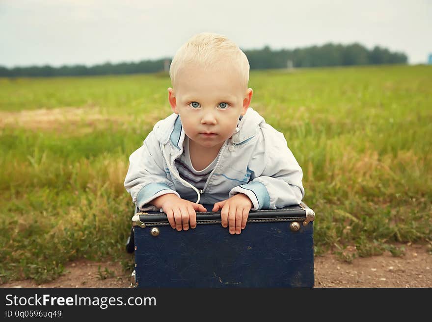 Little boy sitting on a suitcase. child traveler