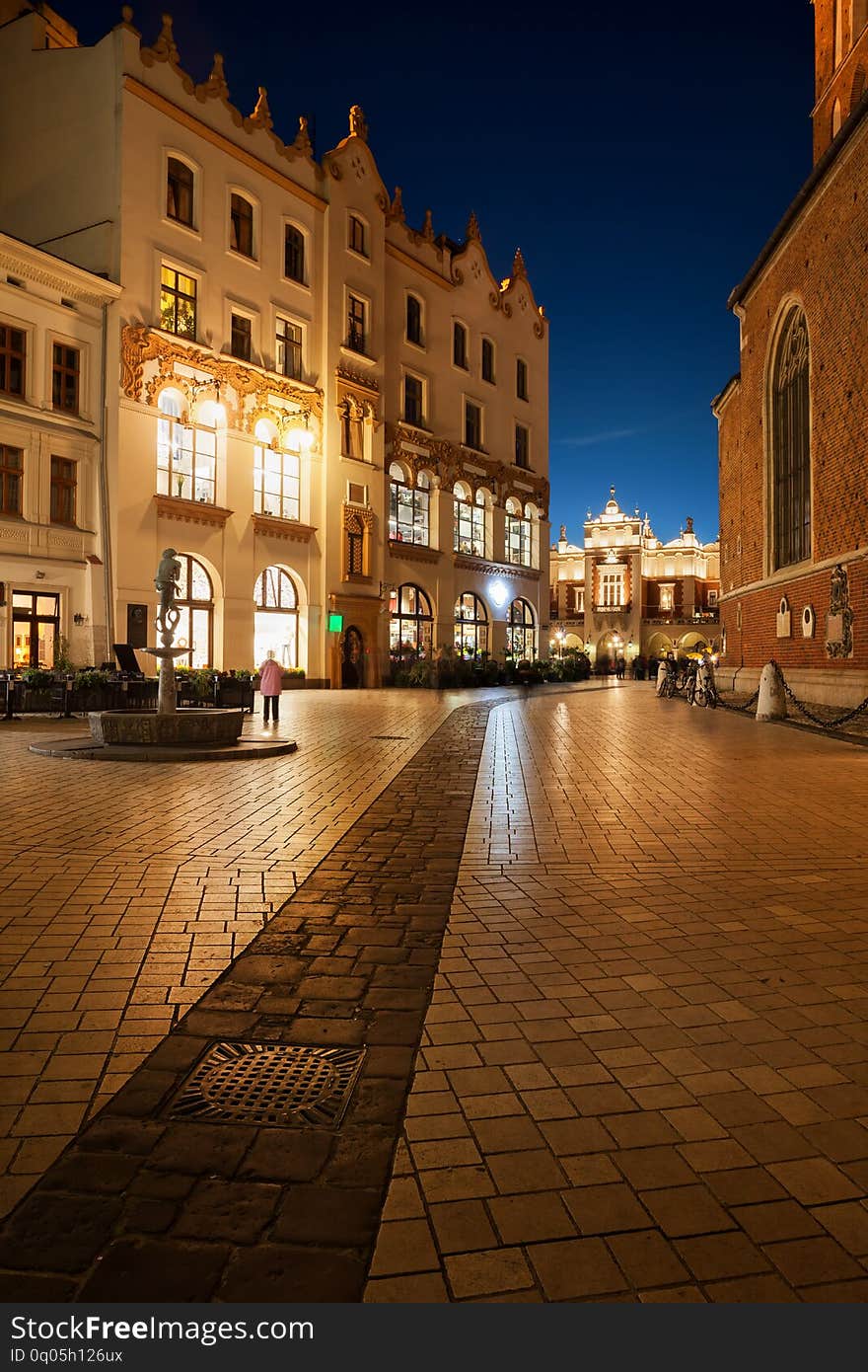 Old Town in Krakow by night in Poland, cobblestone Mariacki Square with Art Nouveau Czynciel House, historic city center. Old Town in Krakow by night in Poland, cobblestone Mariacki Square with Art Nouveau Czynciel House, historic city center