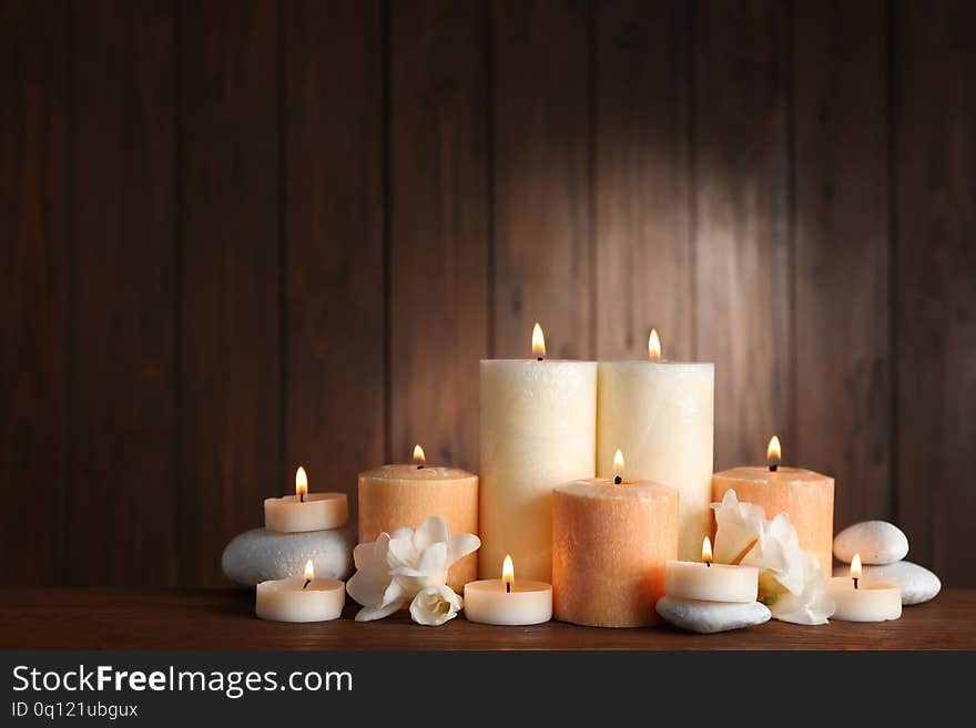 Beautiful Composition With Candles, Flowers And Stones On Table Against Wooden Background