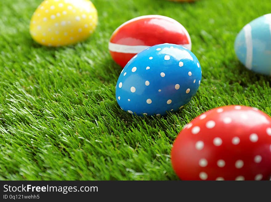 Colorful painted Easter eggs on green grass, space for text