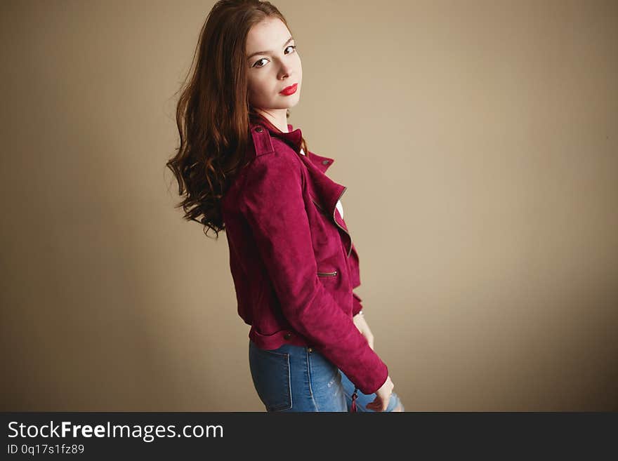 Young hipster woman clothed in magenta jacket. Beautiful eyes, long brown curly hair.