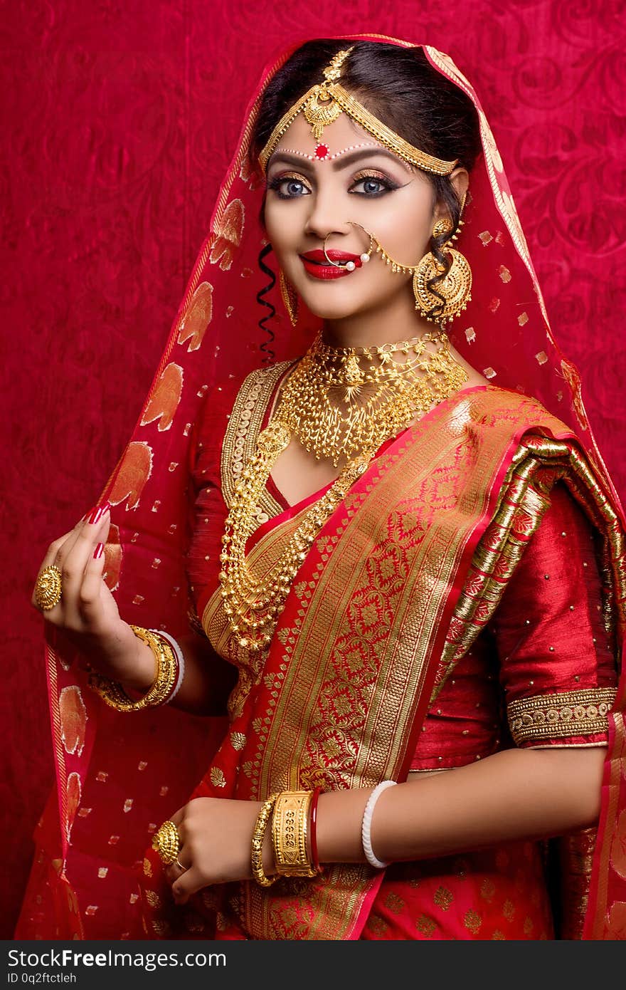 Portrait of young Indian bride wearing gold jewelry and red sari in wedding