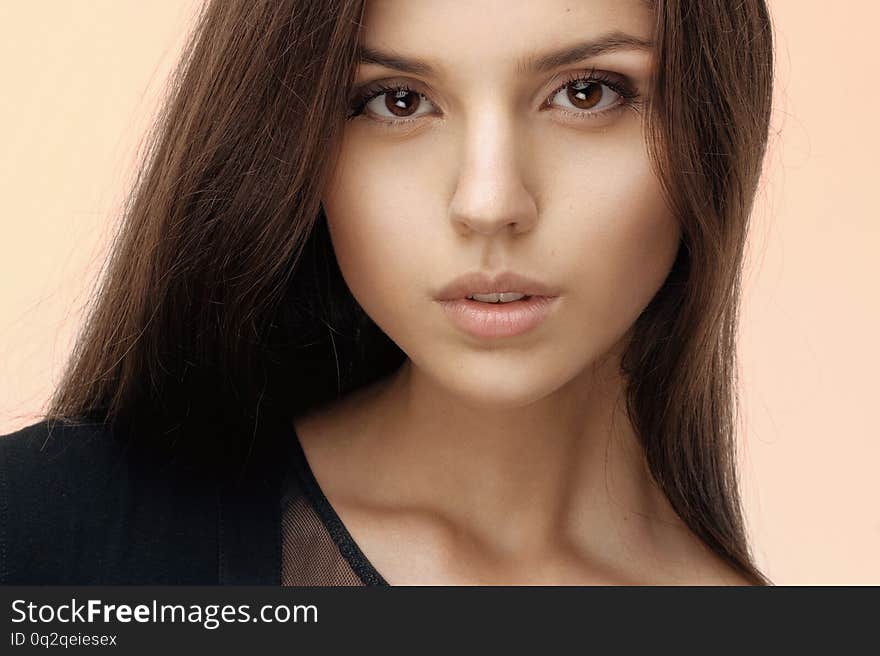 Close up of a brunette girl with seductive and natural make up, long hair, looking at camera, dressed in black.