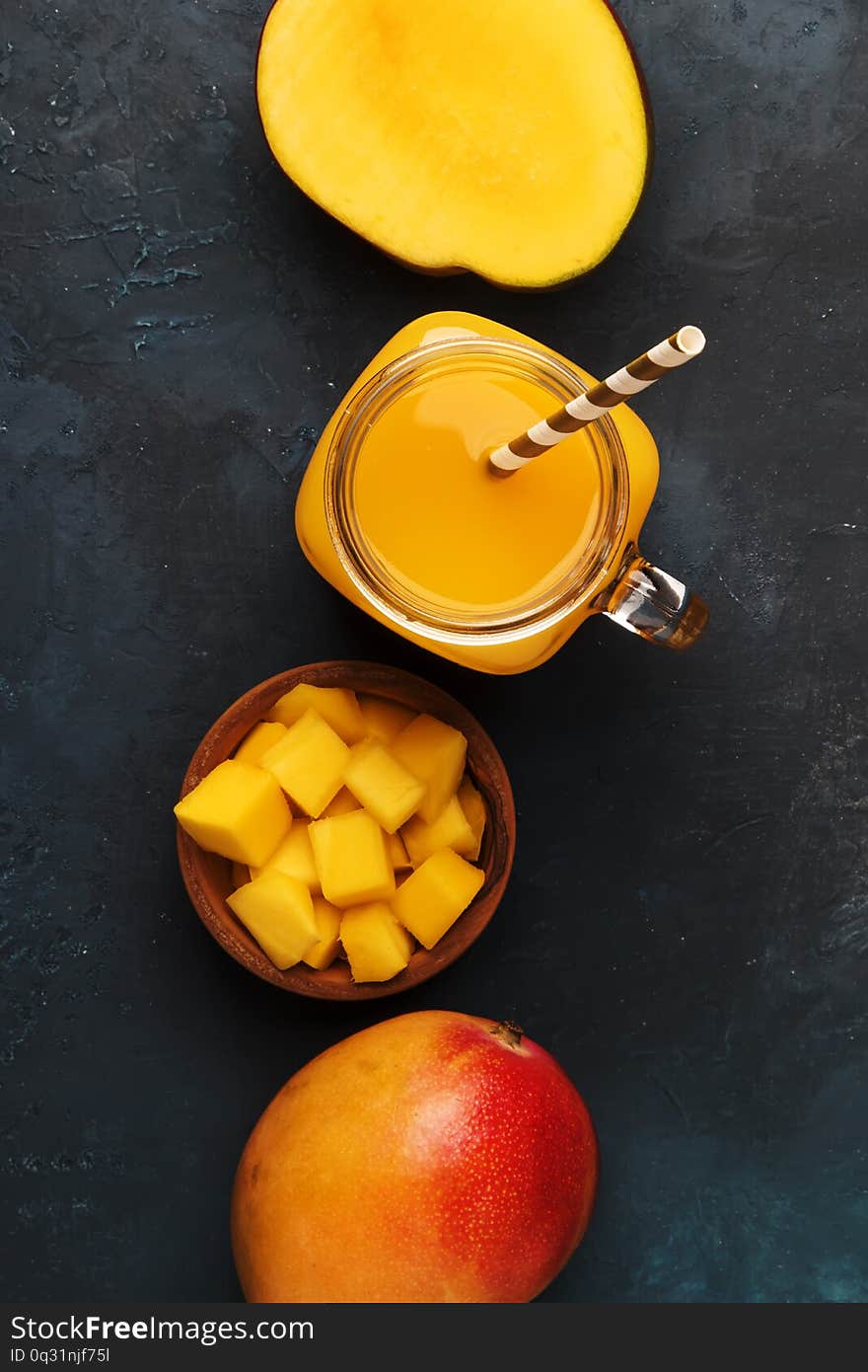 Mango smoothie in glass jar with fresh fruit on blue background, copy space, top   view