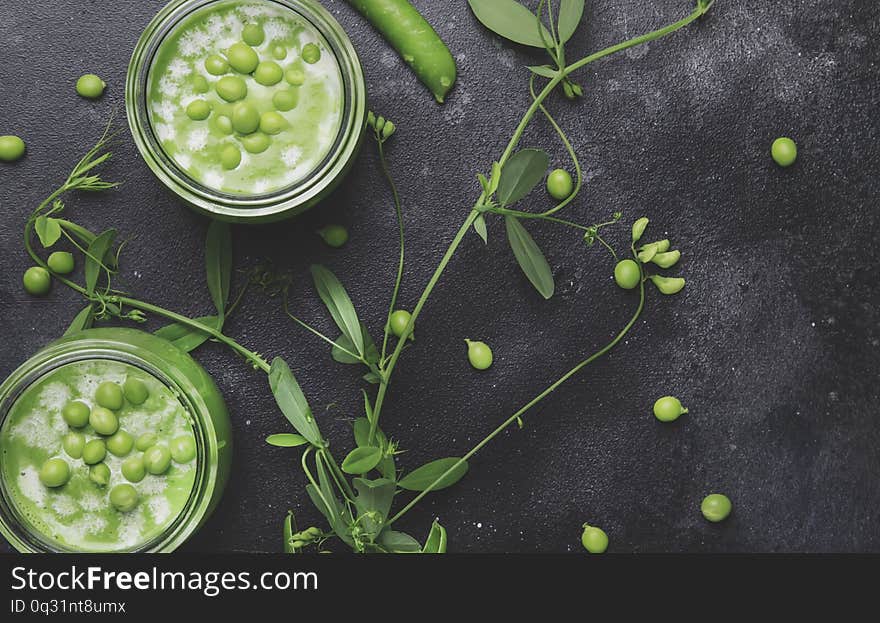 Cream green peas soup in glass jar on gray kitchen table, copy space, selective  focus