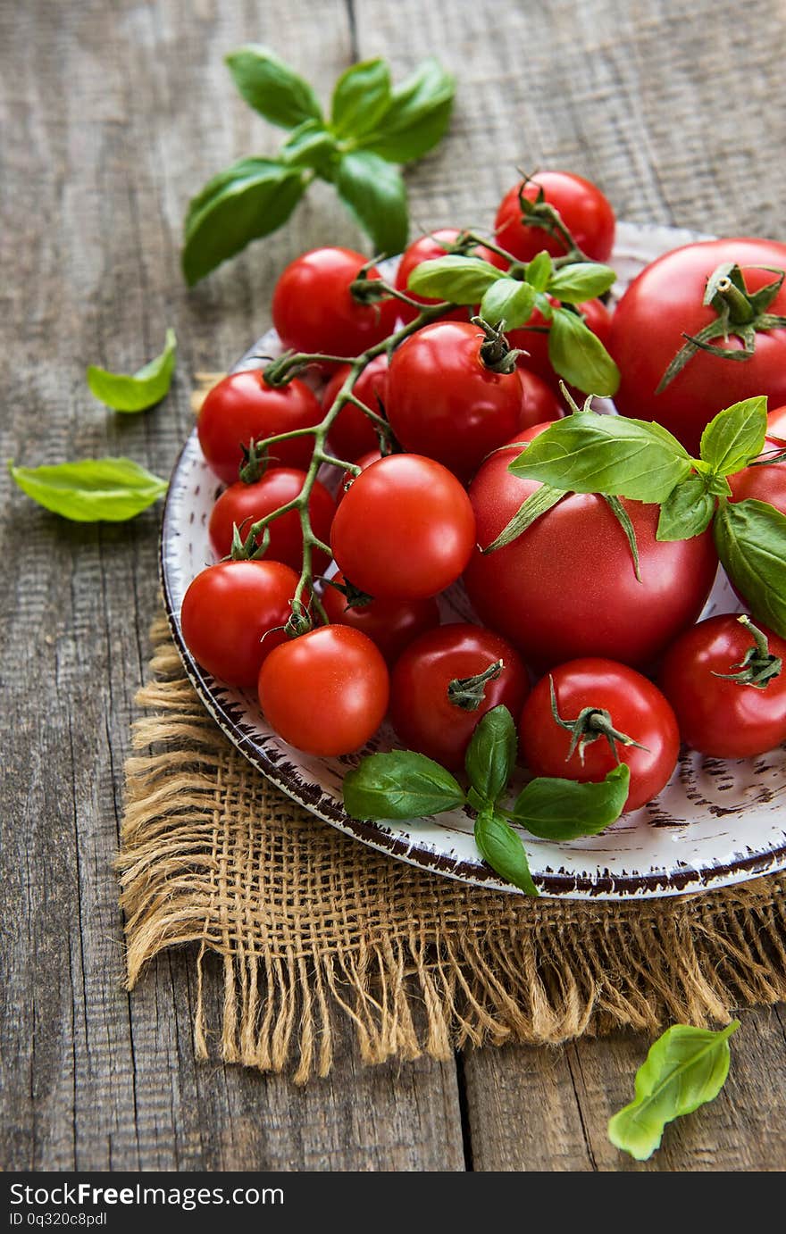 Plate with tomatoes and green basil on a wooden table