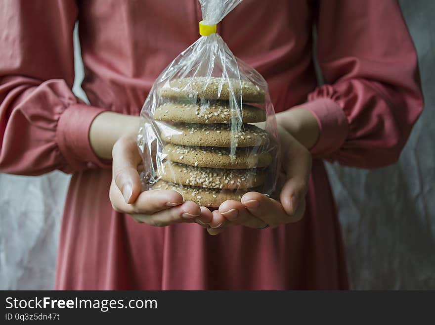 Oat cookies. A girl is holding a package with oatmeal cookies. Closeup front view.