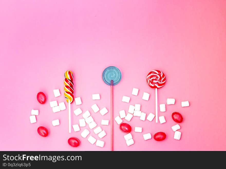 Flat lay composition with yummy lollipops and marshmallows and space for text on pink background. Different sweets. Copy space