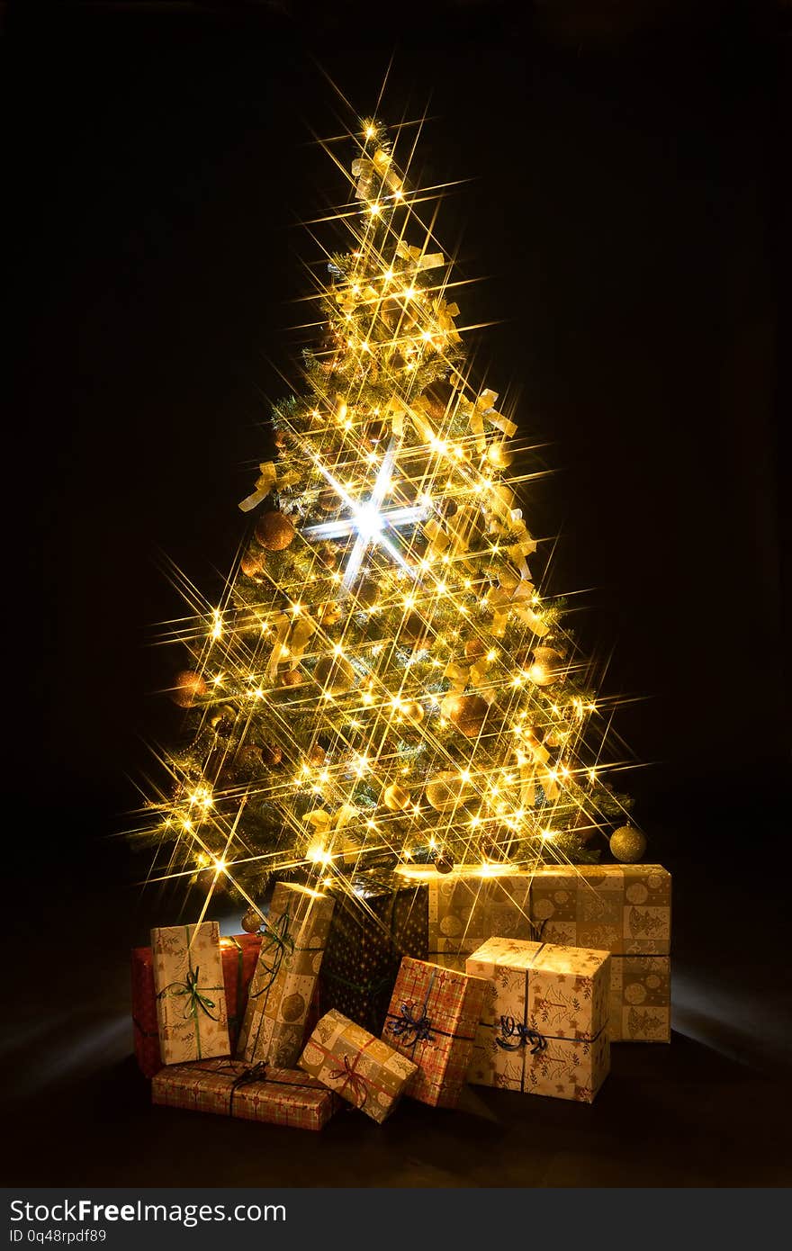 Gifts and golden Christmas tree bokeh in a black background