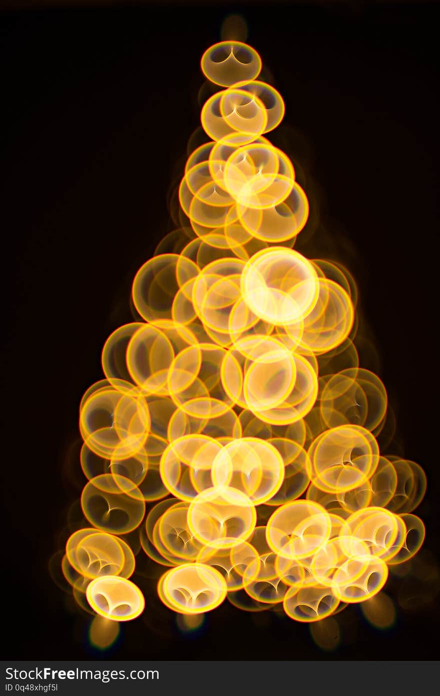 Golden Christmas tree with decorations and lights bokeh in a black background. Golden Christmas tree with decorations and lights bokeh in a black background